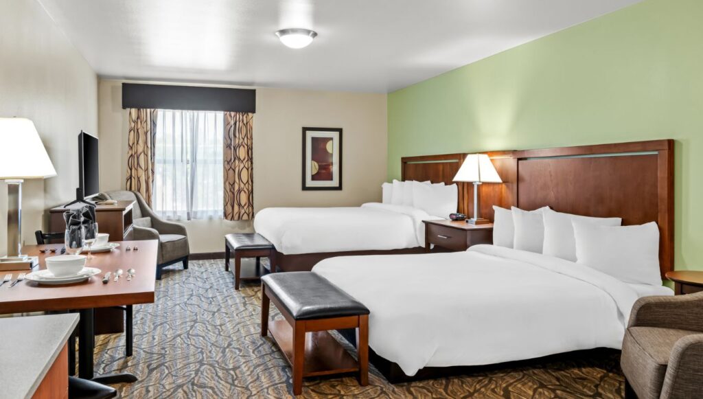 Ledgestone Hotel Vernal - Room with 2 beds, ottomans, dining table, TV and corner chairs
