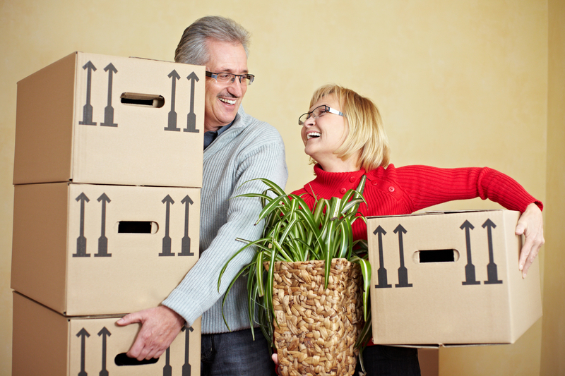 a couple carrying boxes into their new home